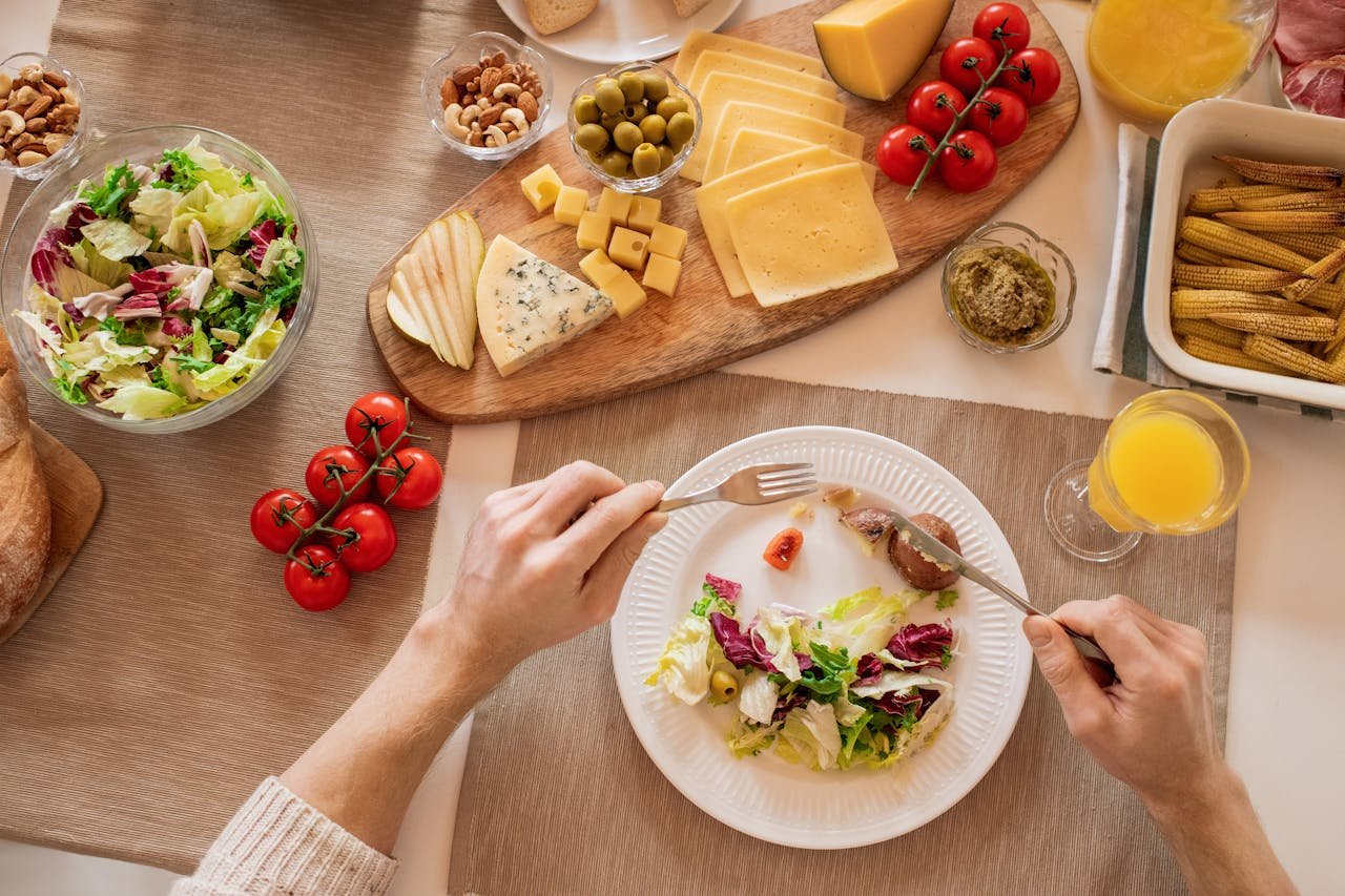 Overhead view of a cheese platter with fresh salad and juice, perfect for a gourmet lunch setting.